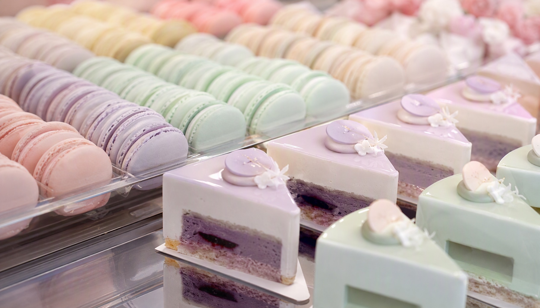 Витрина macaron-ателье: ряды макарон пастельных оттенков на стеклянных полках, мягкий студийный свет